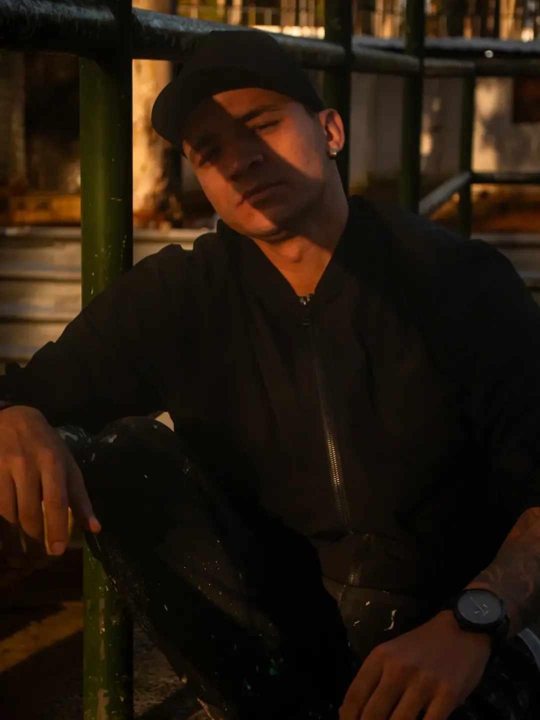 Homem de boné e camisa escura sentado, com o rosto iluminado pela luz da tarde.