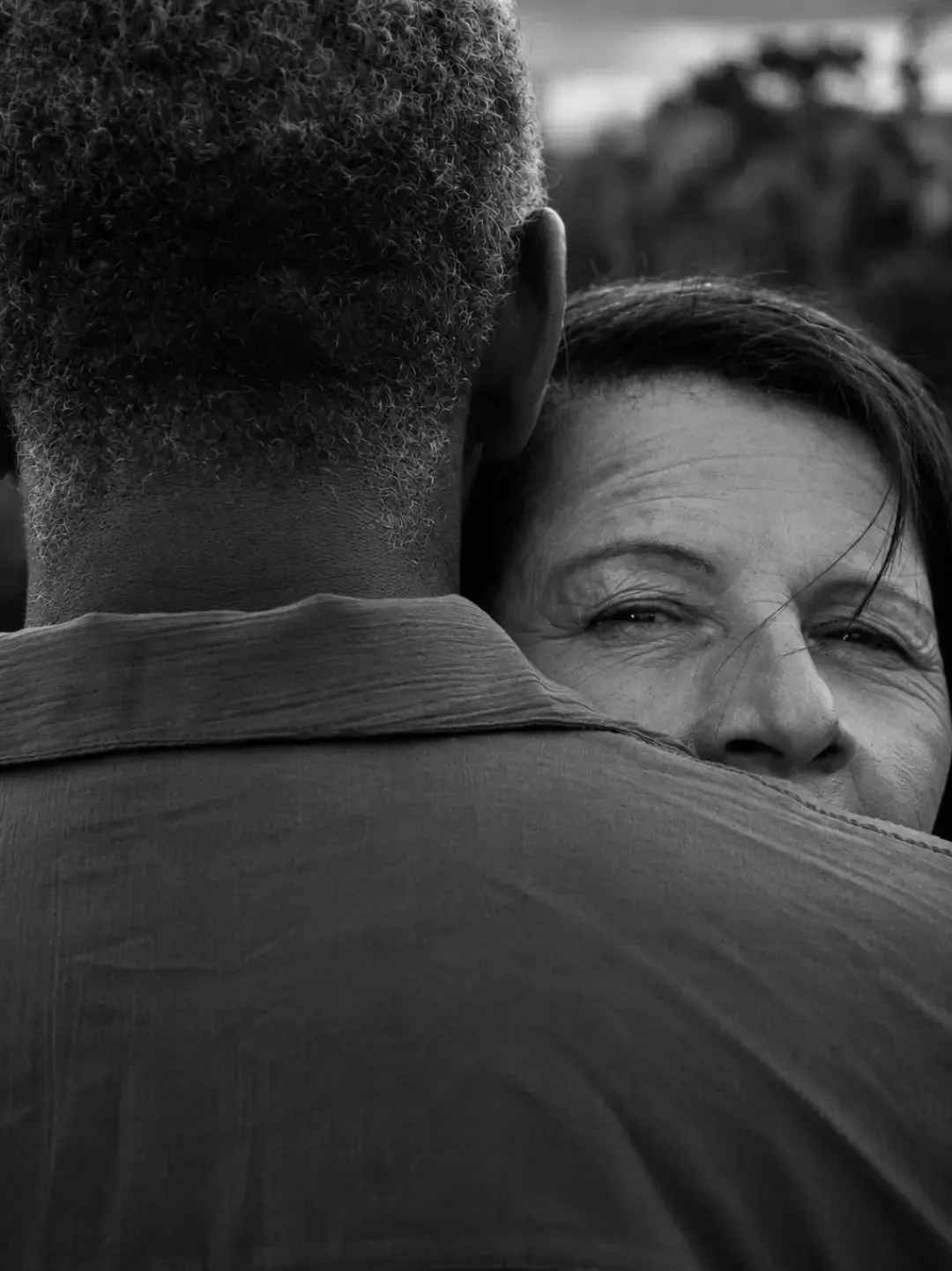 Fotografia em preto e branco de uma mulher sorrindo enquanto abraça um homem.